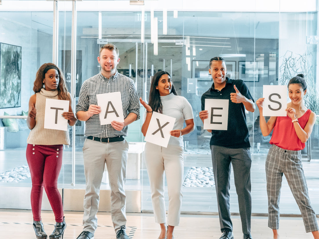 A group of people standing in a line holding up letters that spell "taxes"