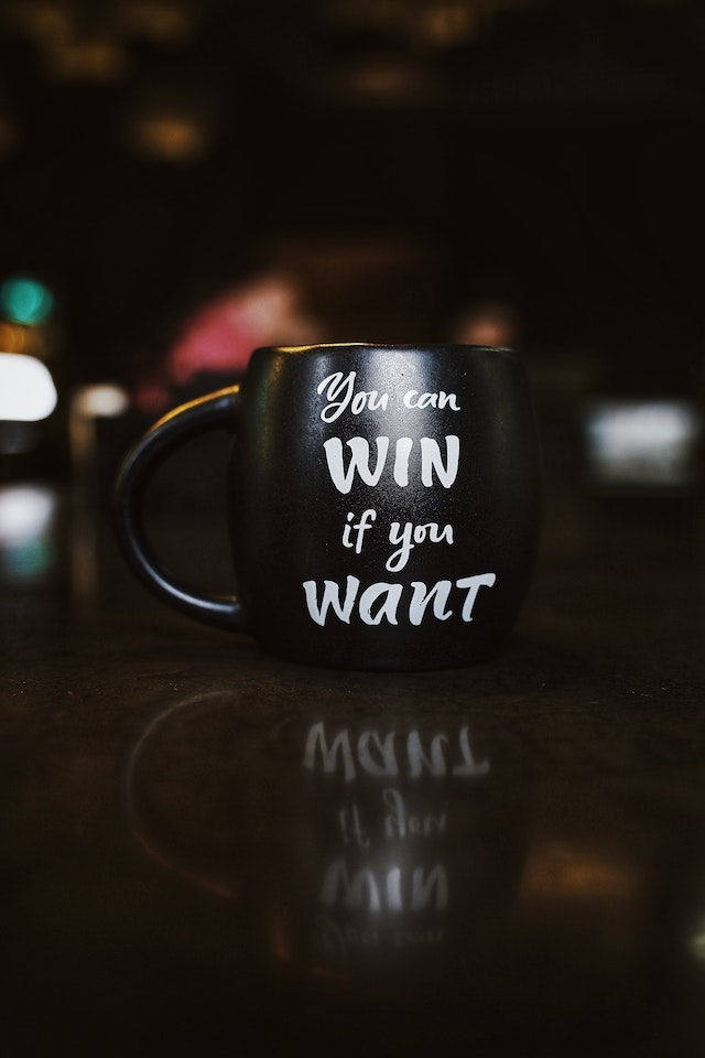 coffee mug on a desk with the words you can win if you want